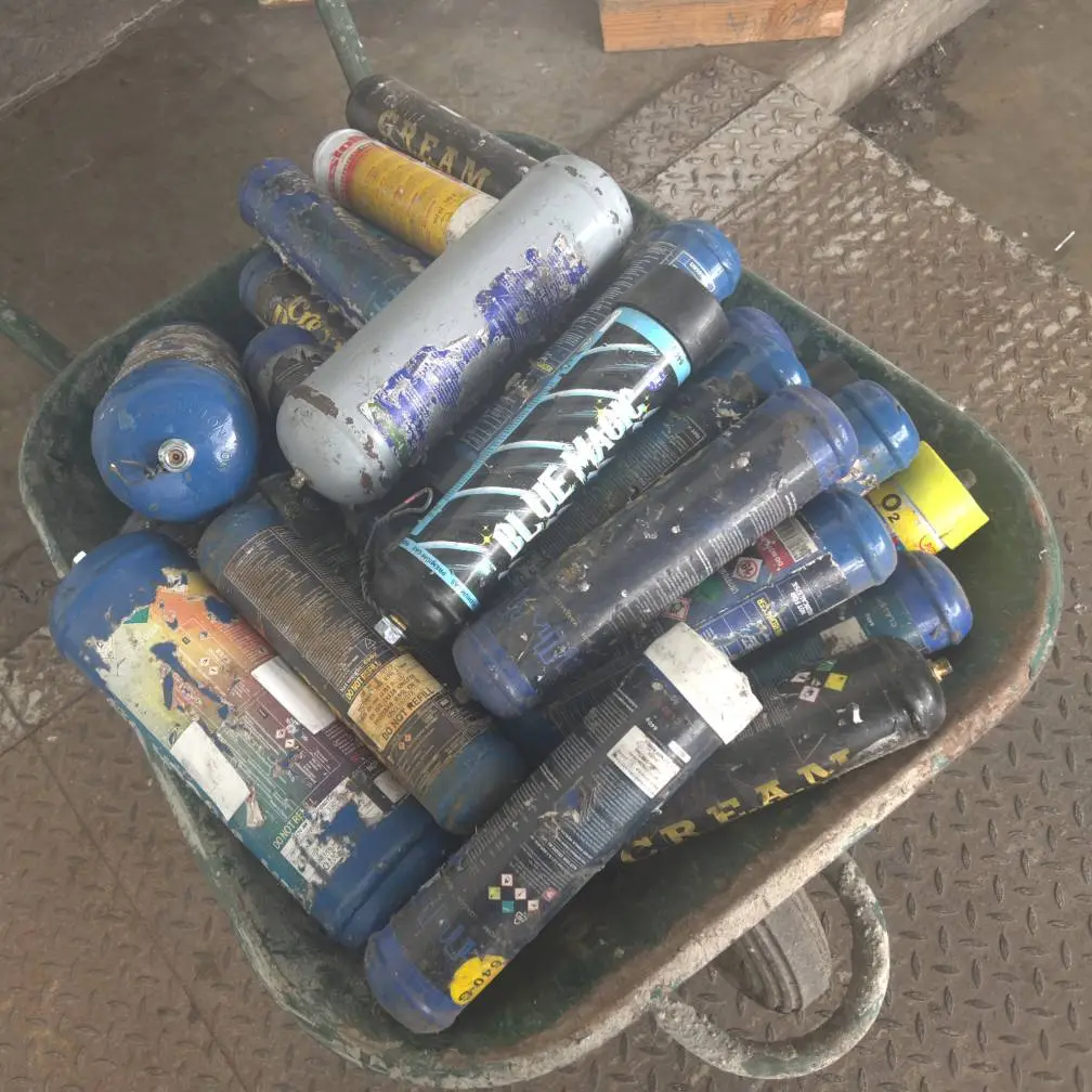 Photographie d'un tas de bouteilles de protoxyde d'azote (N2O) extrait dans un centre de tri